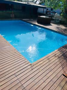 a large blue swimming pool with a wooden deck at Tshedza Guest House in Pretoria