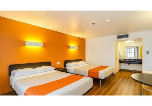 two beds in a hotel room with orange walls at Motel 6-Carlsbad, CA Beach in Carlsbad