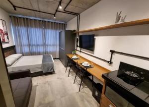 a room with a bed and a desk and a television at Apto Studios in Itajaí