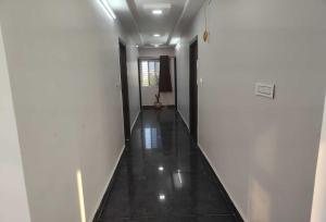 an empty hallway with white walls and a black floor at Hotel O Kurnool Railway Station Road in Kurnool +8 photos