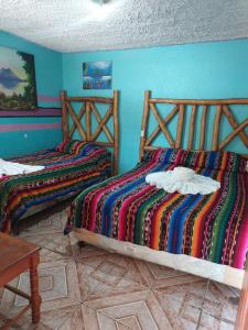 two beds in a room with blue walls at Hotel Casa Ramos in Panajachel