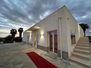 a white building with a red rug in front of it at Casa della Cittadella in Noto
