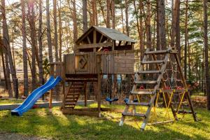 a tree house with a slide and a ladder at Nadmorski Bursztyn - Błękitna in Rowy