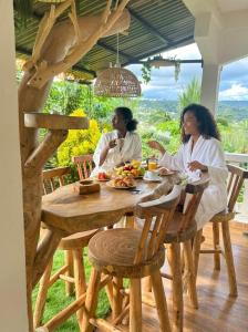 two women sitting at a wooden table with food at LESSENCIEL Villa in Sada