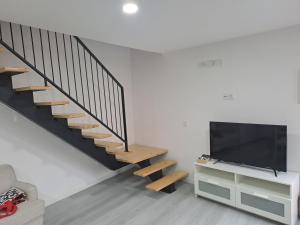 a living room with a staircase and a flat screen tv at Casa da Figueira in Aguiar da Beira