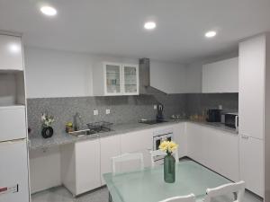 a kitchen with a glass table and white cabinets at Casa da Figueira in Aguiar da Beira
