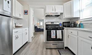 a kitchen with white cabinets and a stove top oven at Beach Block Ocean Views steps from the boardwalk in Ocean City +5 photos