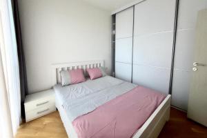 a small bedroom with a bed with pink pillows at Boreti Apartment in Budva