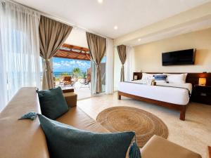 a bedroom with a bed and a television and a couch at Noah Beach Hotel & Suites in Mahahual