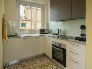 a kitchen with white cabinets and a microwave at Testa tra le Nuvole - Attico con Terrazza panoramica in centro in Novi Ligure