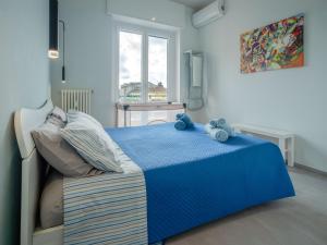a bedroom with a blue bed and a window at Testa tra le Nuvole - Attico con Terrazza panoramica in centro in Novi Ligure