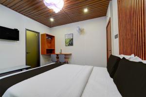a bedroom with a bed and a desk and a tv at Super Hotel O AM Grandd in Kāraikkudi +22 photos