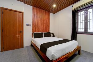 a bedroom with a large bed and a wooden door at Super Hotel O AM Grandd in Kāraikkudi