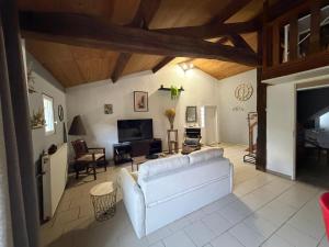 a living room with a white couch and a tv at Maison à la campagne avec piscine privée et balnéo in Sendets