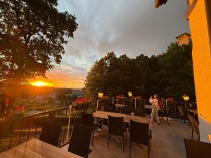 a woman standing on a balcony with a sunset in the background at Attikos Hotel & Restaurant in Lengenfeld