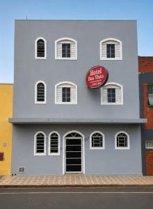 a building with a red sign on the side of it at Hotel Boa Vista in Assis