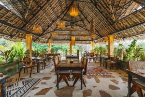 ein Restaurant mit Tischen und Stühlen und einer großen Decke in der Unterkunft Oke Ani Boutique Hotel in Paje