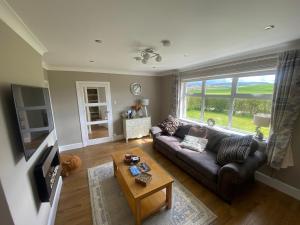 a living room with a couch and a table at 1 Shawsmuir Cottage in Thornhill