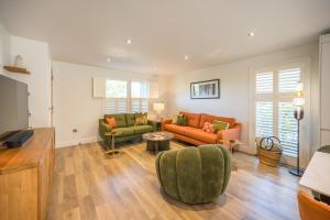 a living room with two couches and a tv at Orange House, Southwold in Southwold