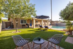a yard with chairs and an umbrella and a pool at Chandler Galveston in Chandler