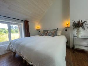 a bedroom with a white bed with a window at La maisonnette in Saussemesnil