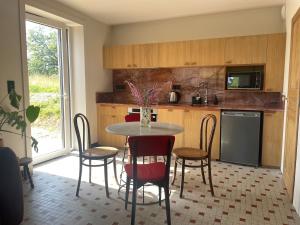 a kitchen with a table and chairs and a kitchen with a window at La maisonnette in Saussemesnil