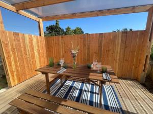a wooden table on a deck with a wooden fence at La maisonnette in Saussemesnil