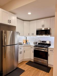 a kitchen with white cabinets and a stainless steel refrigerator at BP STAYS - Hotel-Style, No Host, Professionally Managed ID312 in Jersey City