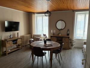 a living room with a table and chairs and a television at Gîte NAO in Serves-sur-Rhône