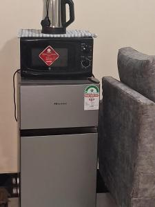 a microwave on top of a refrigerator next to a couch at Town Stays in Voi