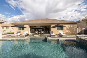 a house with a swimming pool with chairs and umbrellas at Queen Creek on 193rd in Queen Creek