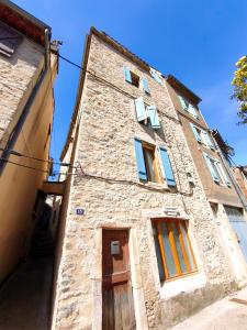 an old stone building with windows and a door at L'aube de Pierre in Saint-Pons-de-Thomières