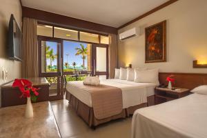 a hotel room with two beds and a balcony at Quinta do Sol Praia Hotel in Porto Seguro