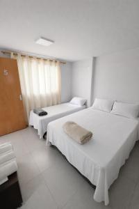 two beds in a room with white walls at DunnaAP Smart Studios in Catalão