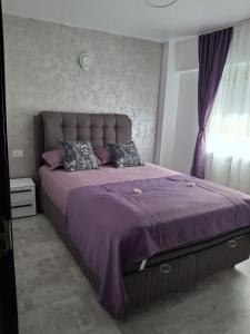 a bed in a bedroom with a purple bedspread at Ioana Home in Râmnicu Vâlcea