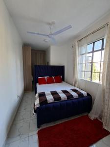 a bedroom with a blue bed with red pillows and a window at cozy 1bedroom mombasa bamburi near the beach with hot shower, Netflix, Secured parking 07&07 for 95 then 61to18 in Mombasa