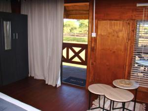 a bedroom with two chairs and a door with a balcony at Chobe Lesoma Chalets Hotel in Lesoma +29 photos