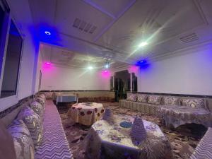 a room with couches and a table and purple lights at Red Rocks Guest House in Tamellalt
