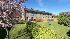 a large brick building with a yard with bushes at Bauernhof Claussen Fehmarn in Fehmarn