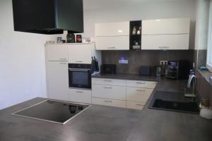 a kitchen with white cabinets and a stove at Treuberg Rooms - Cuxhaven Northside in Cuxhaven
