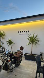 a motorcycle parked in a room with palm trees at Hotel Kappa3 Villas in Vlorë