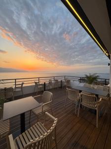 a deck with tables and chairs and a sunset at Hotel Kappa3 Villas in Vlorë