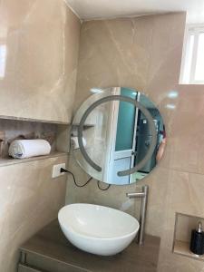 a bathroom with a round mirror and a sink at Dalejadrohouse in Baños
