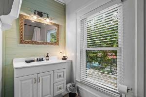 a bathroom with a sink and a mirror and a window at Old Carrabelle Hotel Magnolia Suite in Carrabelle