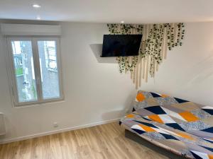 a bedroom with a bed and a tv on a wall at Jasmin in Saint-Aignan