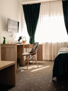 a bedroom with a chair and a desk with a television at Paunasul Codrilor in Câmpulung Moldovenesc