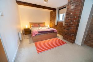 a bedroom with a bed and a brick wall at Rustic 2BR Loft Exposed Brick & Beams in Liverpool