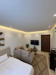 a bedroom with a bed and a couch and a tv at أستديو حديث عصري in Ath Thuqbah