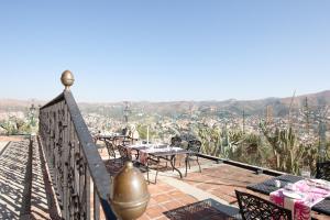 a balcony with tables and chairs and a view of a city at Misión Grand Casa Colorada in Guanajuato