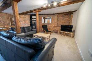 a living room with a leather couch and a tv at Rustic 2BR Loft Exposed Brick & Beams in Liverpool